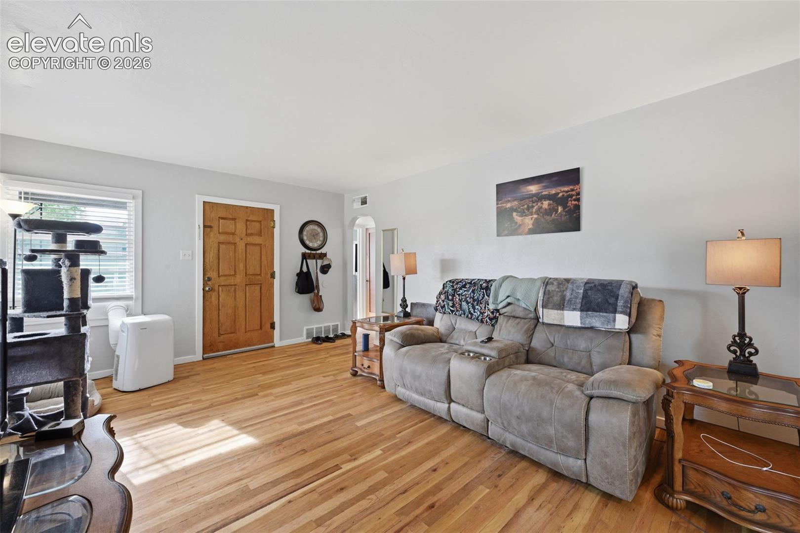 Hardwood flooring throughout, light gray wall paint, white trim, and a paneled wood entry door