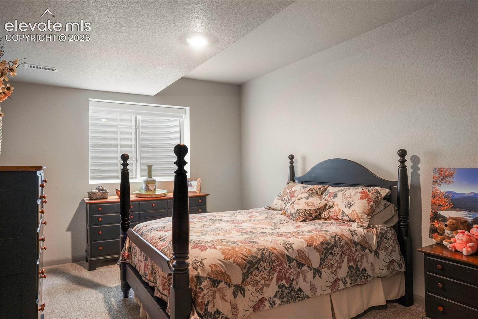 Carpeted bedroom featuring neutral wall tones and a window with blinds