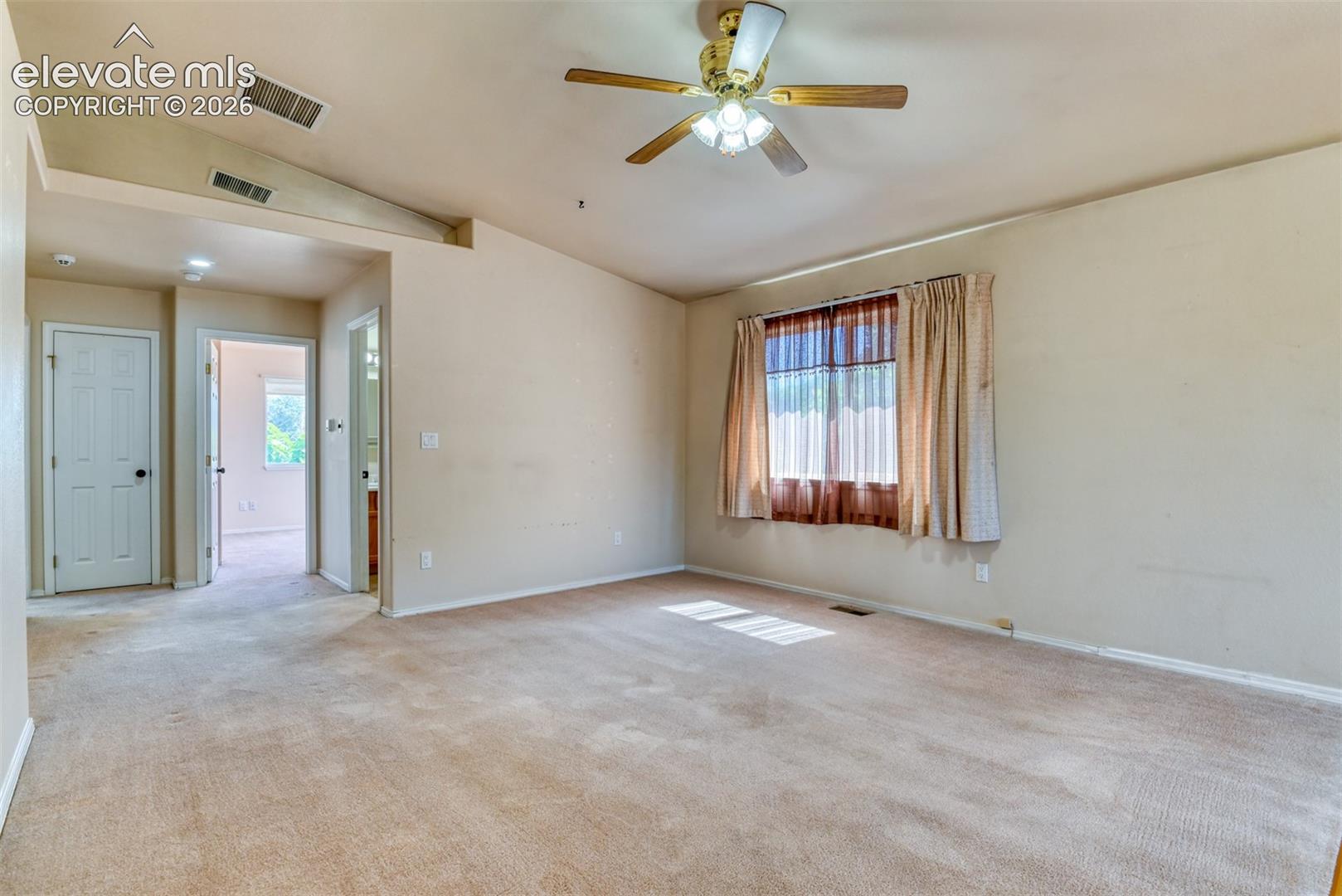 Vaulted ceilings, carpeted flooring, and a central ceiling fan with integrated lighting