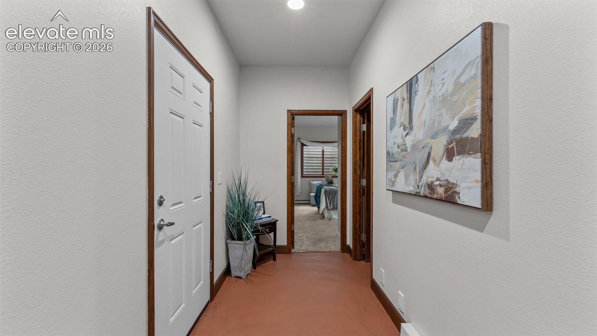 Entryway featuring smooth-finish flooring, white panel door, and wood-toned door casing and trim