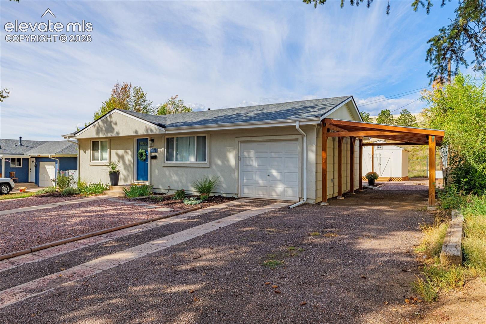Attached single-car garage with attached carport and a detached storage shed