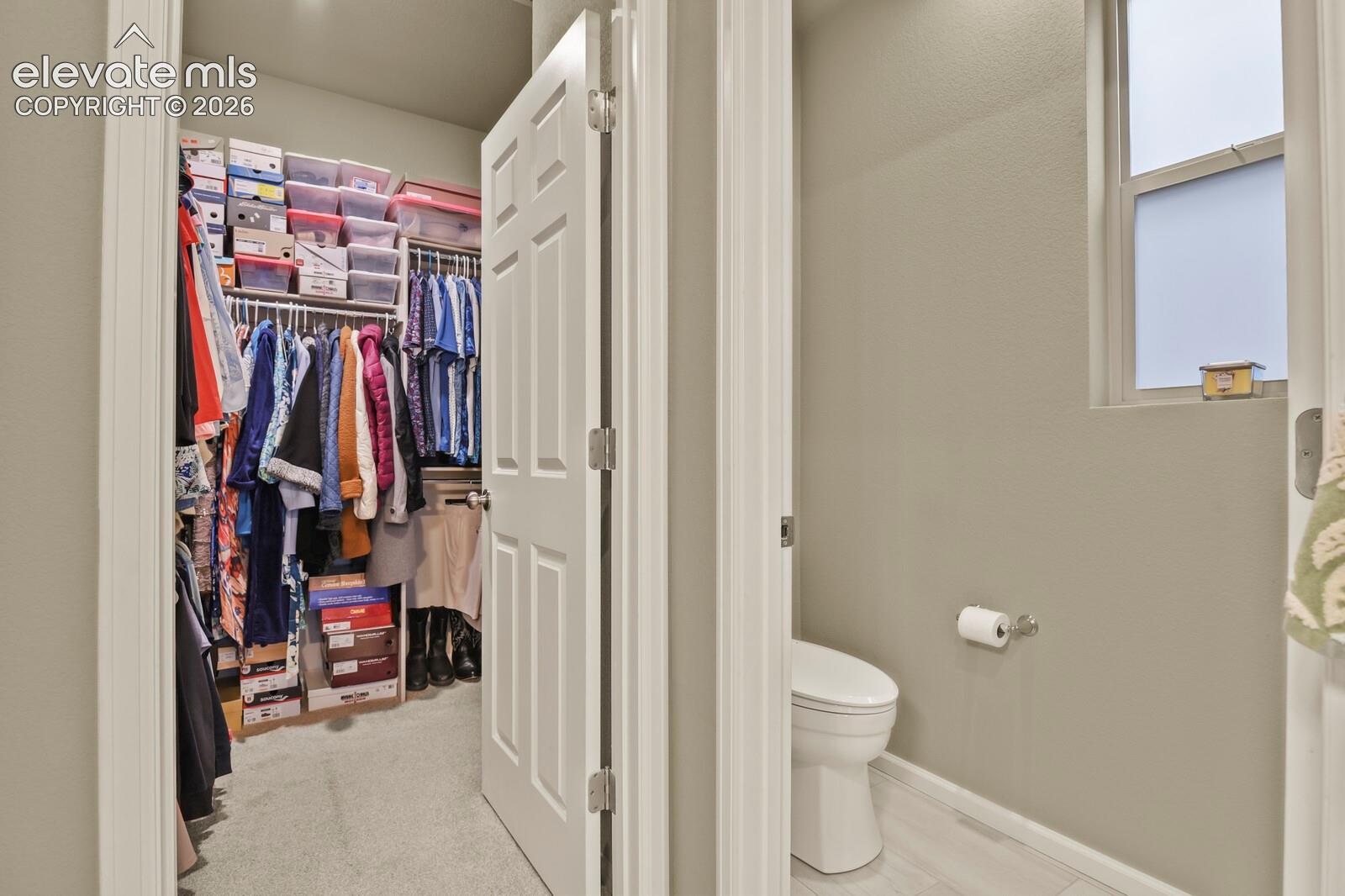 Ample Walk-in closet featuring white wire shelving and a private toilet, bidet with tile and carpet