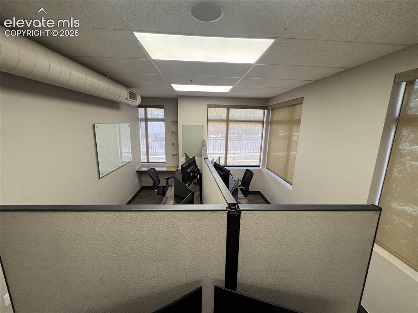 Recessed ceiling lighting, exposed spiral ductwork, built-in desk surfaces, and window blinds