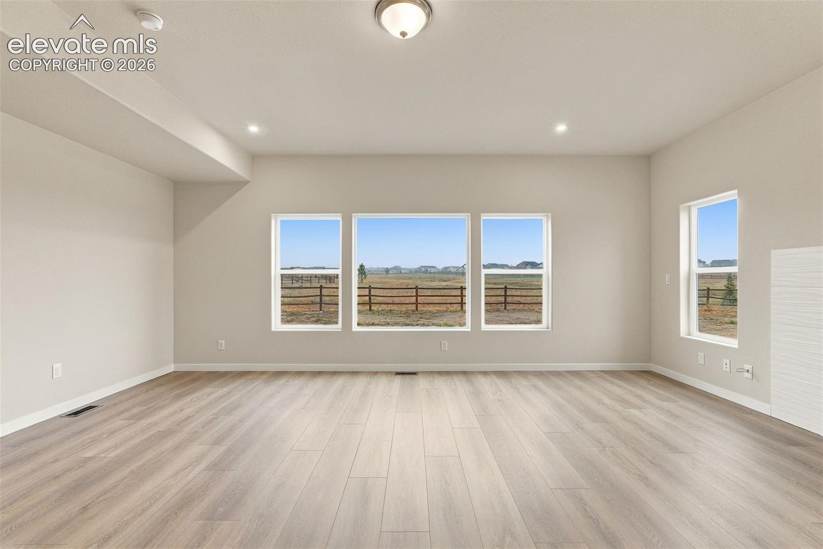 Open-concept interior featuring wood-finish flooring, recessed lighting, and expansive windows highlighting rural scenery
