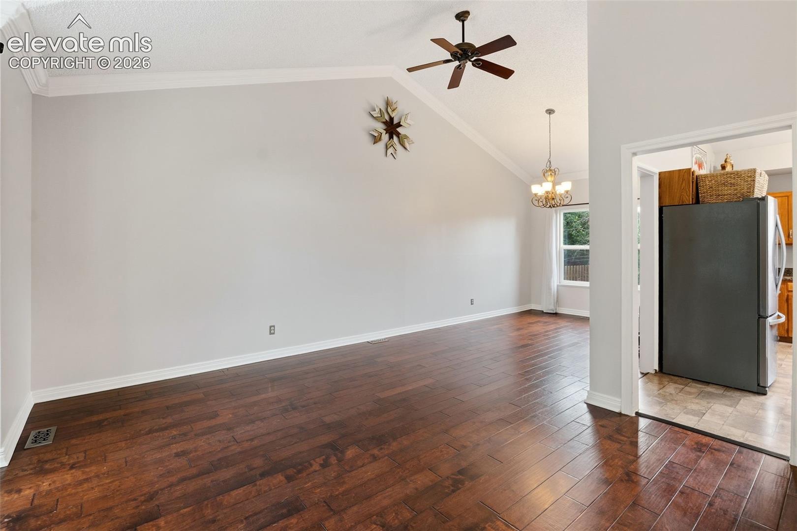 Vaulted ceiling featuring a ceiling fan, crown molding, and wood-finish flooring