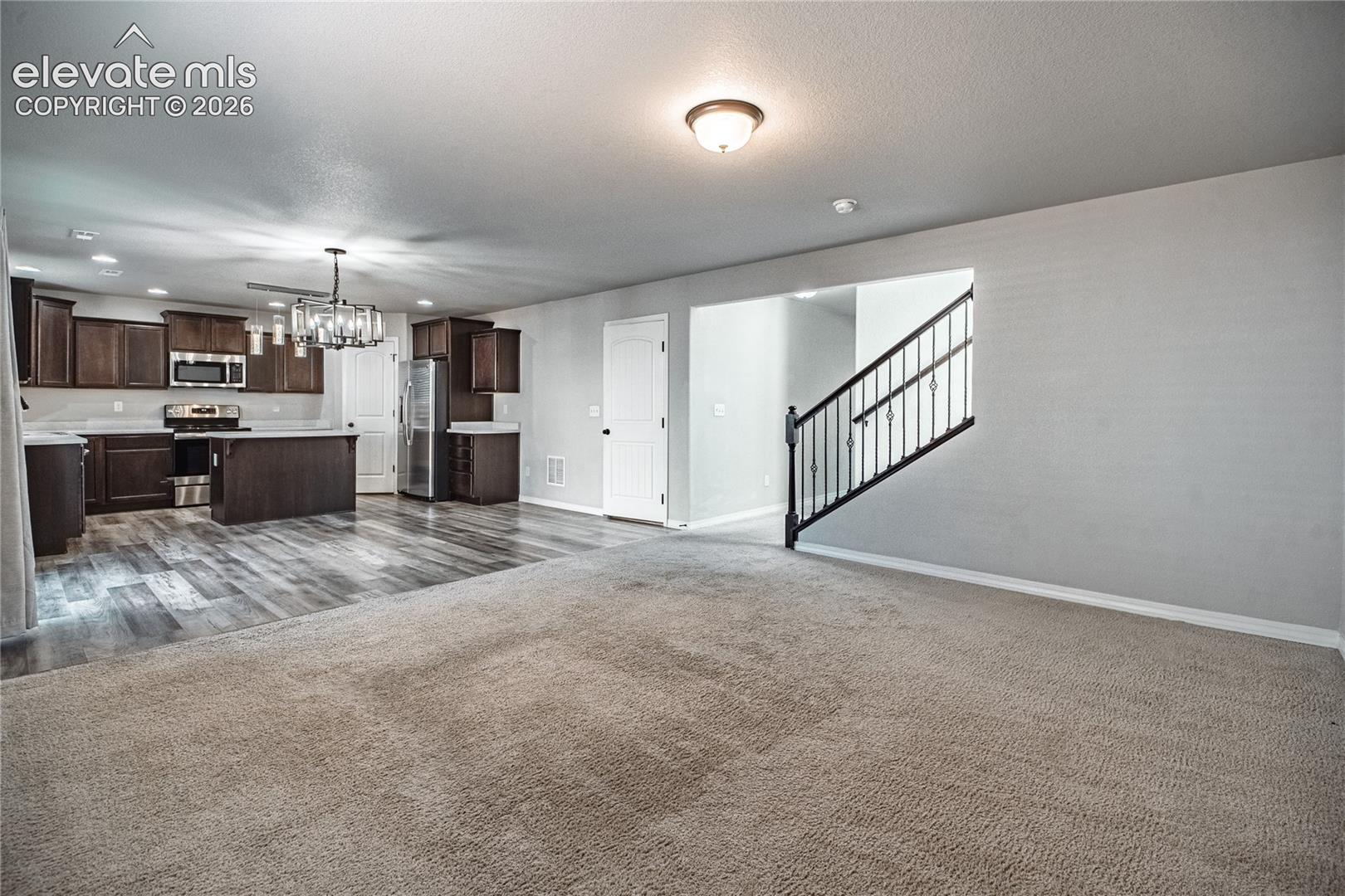 Open-concept living area featuring a kitchen with dark wood-finish cabinetry, stainless steel appliances, and a central island