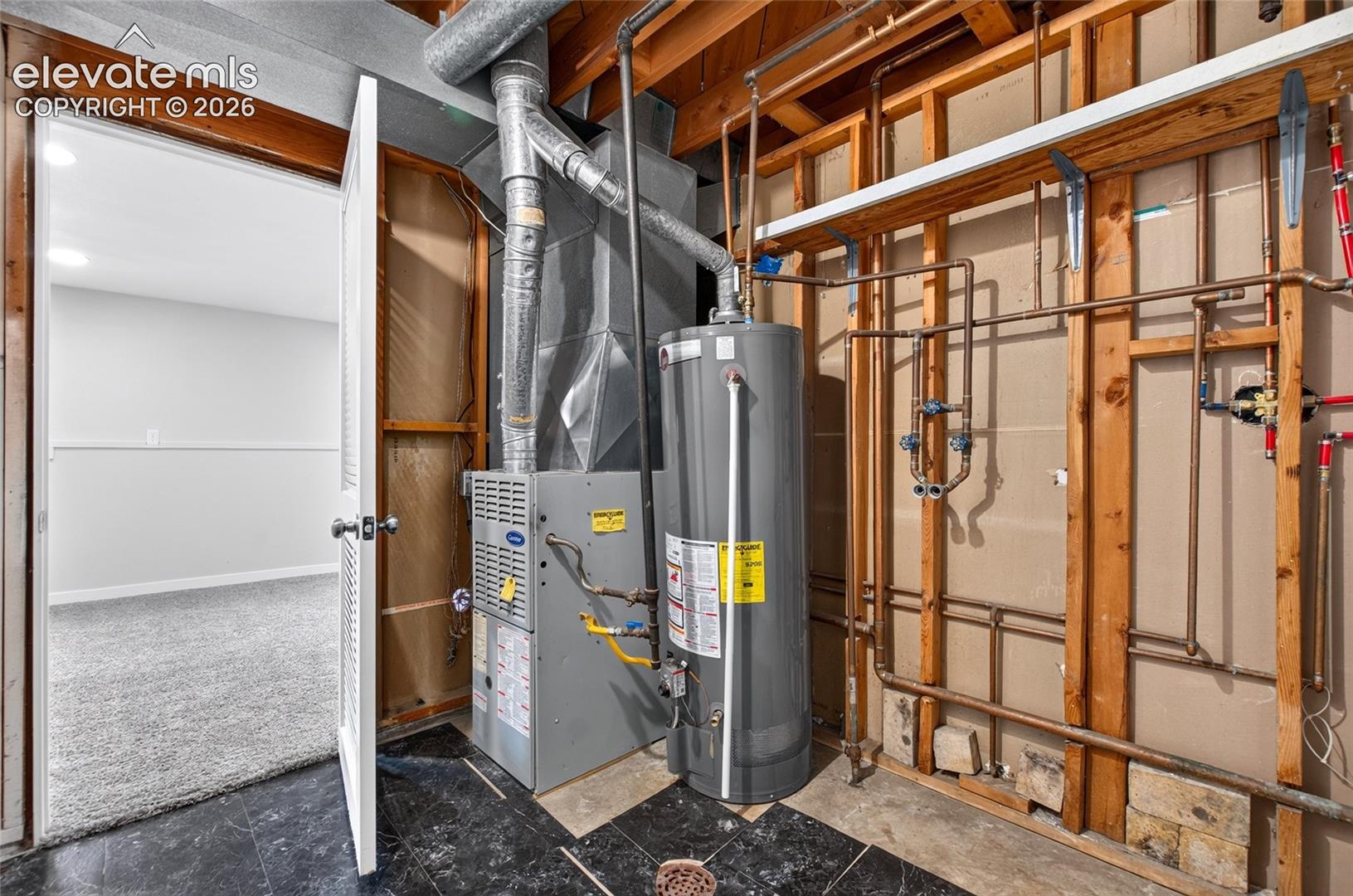 Utility area with a water heater, furnace, exposed copper piping, and ductwork, featuring a tiled floor and an open doorway leading to a carpeted room