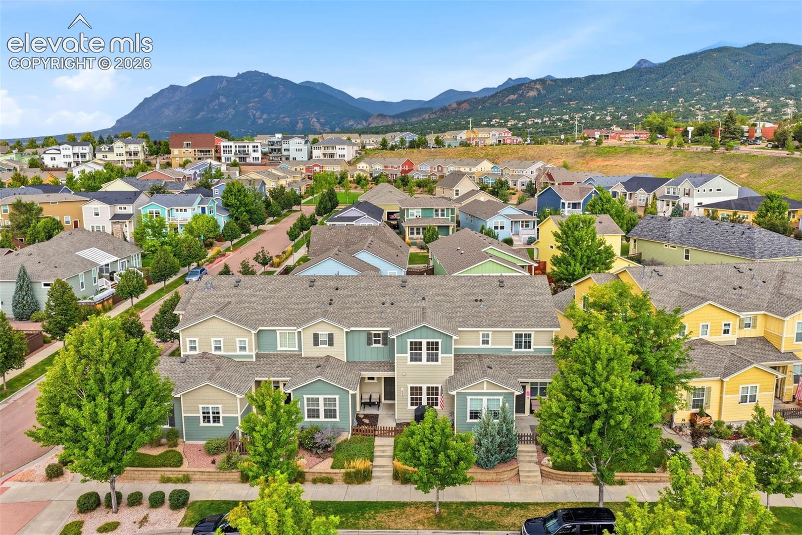 Contemporary townhome community with pitched roofs, varied siding exteriors, and mature trees