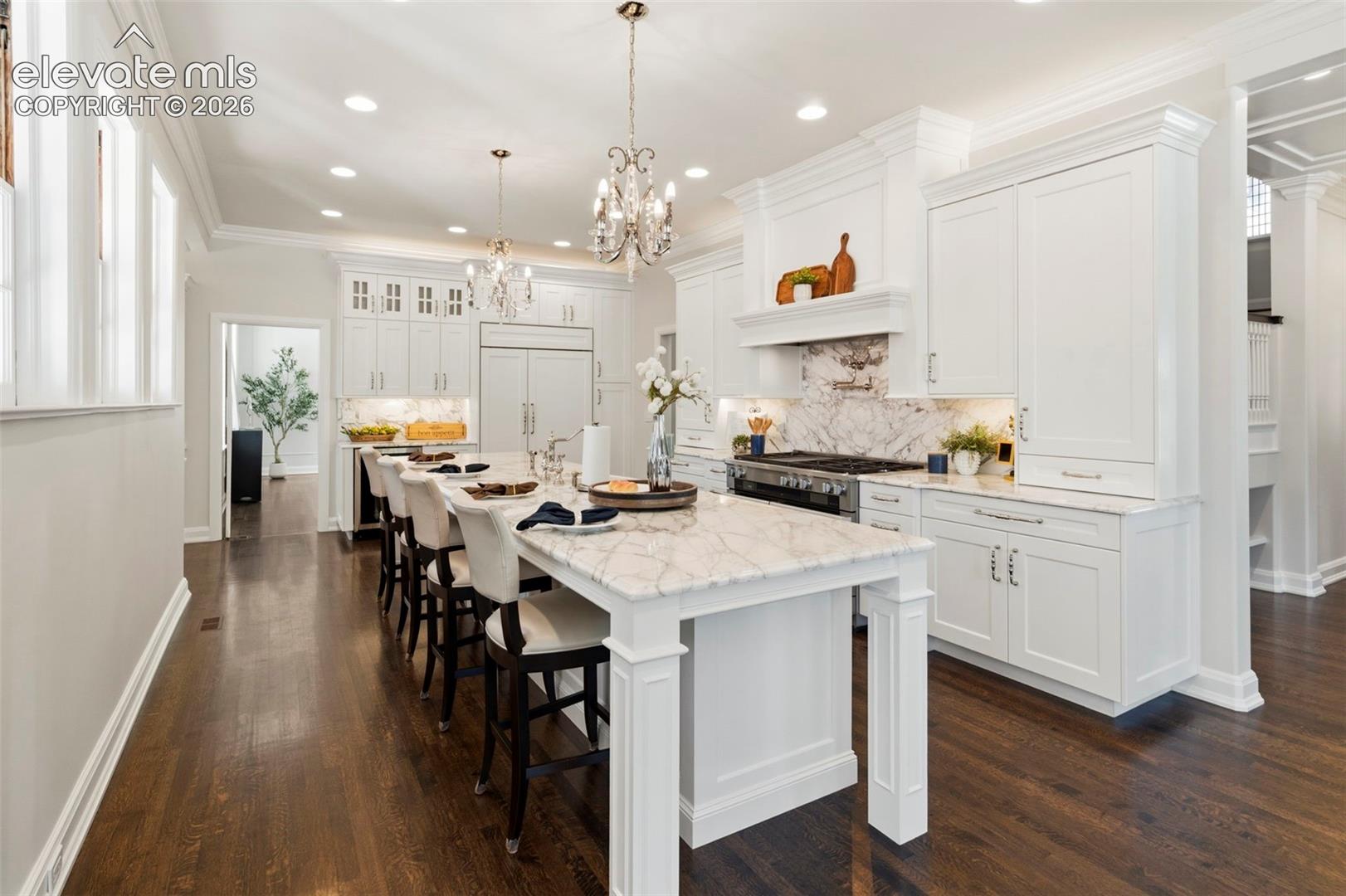 Gourmet kitchen featuring custom white cabinetry, stone countertops, a professional-style range with a decorative hood, recessed lighting, and dark hardwood flooring