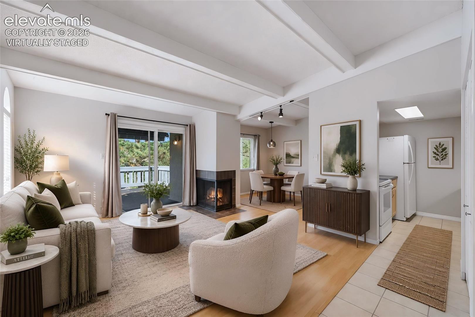 Virtually staged.  Vaulted ceilings with exposed beams, corner fireplace with tile surround, wood-finish flooring, sliding glass door, and skylight