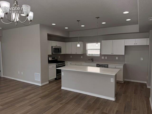 Kitchen featuring white cabinetry, stainless steel appliances, a center island with countertop seating, recessed lighting, and wood-finish flooring
