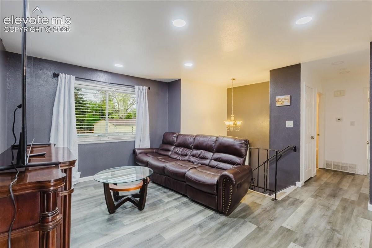 Living area featuring recessed lighting, wood-finish flooring, and a large window with blinds