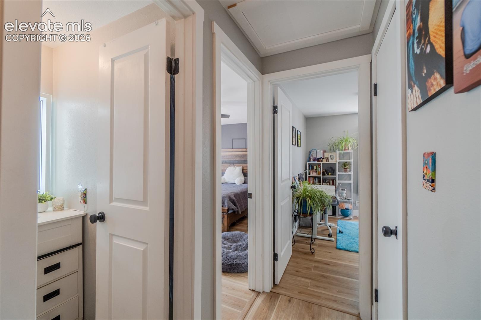 Hallway featuring three panel doors, a built-in three-drawer vanity, and wood-finish flooring