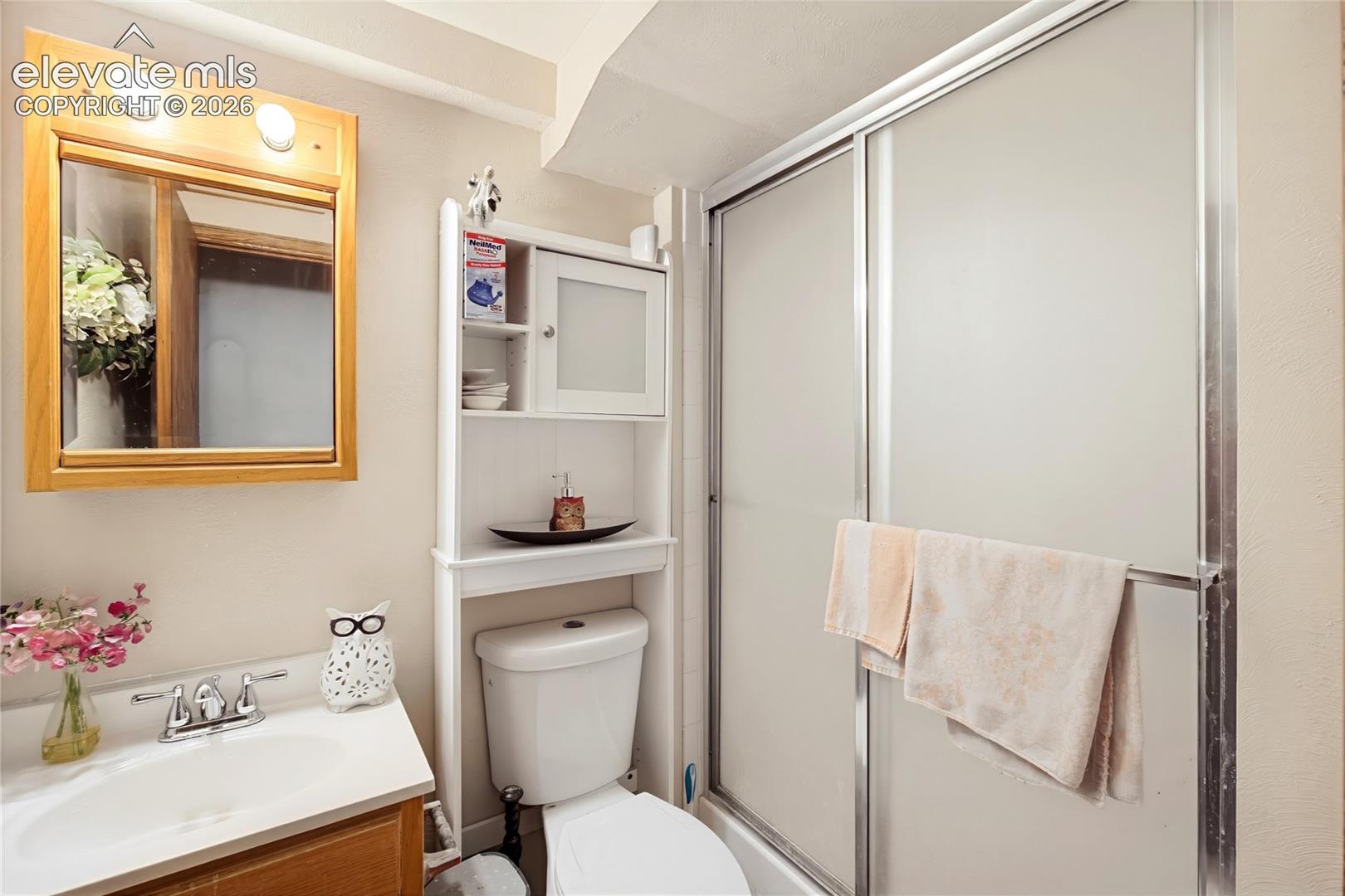 Bathroom featuring a white toilet, built-in storage cabinet, and a shower with frosted glass doors