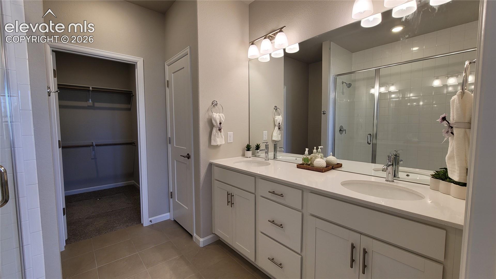 Primary 3/4 Bathroom with double vanities, shower with bench and tile surrounds, cabinet/drawer pulls, quartz countertop, and linen closet! 