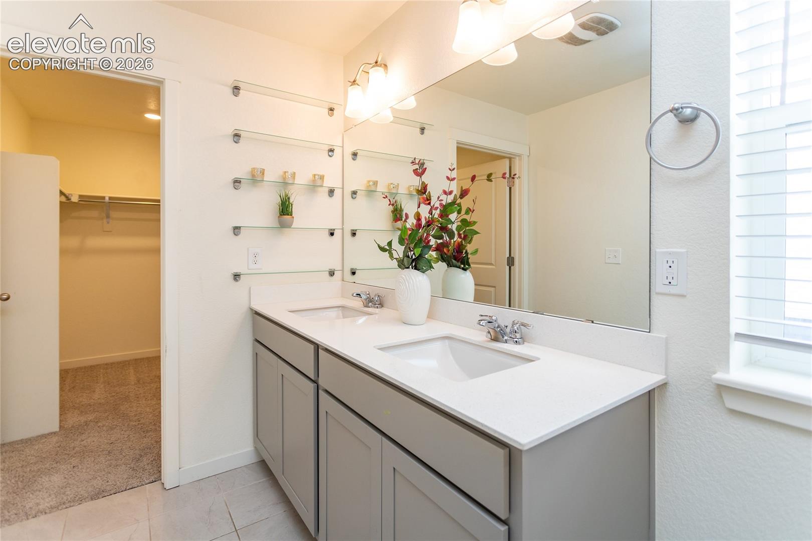 Extended vanity with dual sinks and built-in glass shelving.
