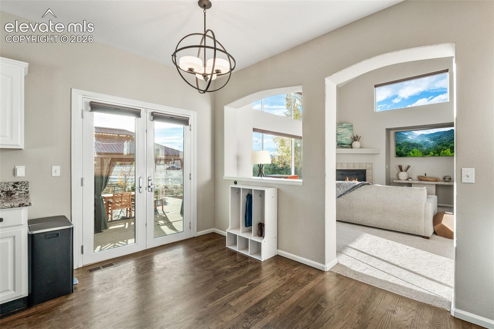 Wood-finish flooring, orb-style chandelier, glass-paned double doors, arched entryway, and recessed display niche