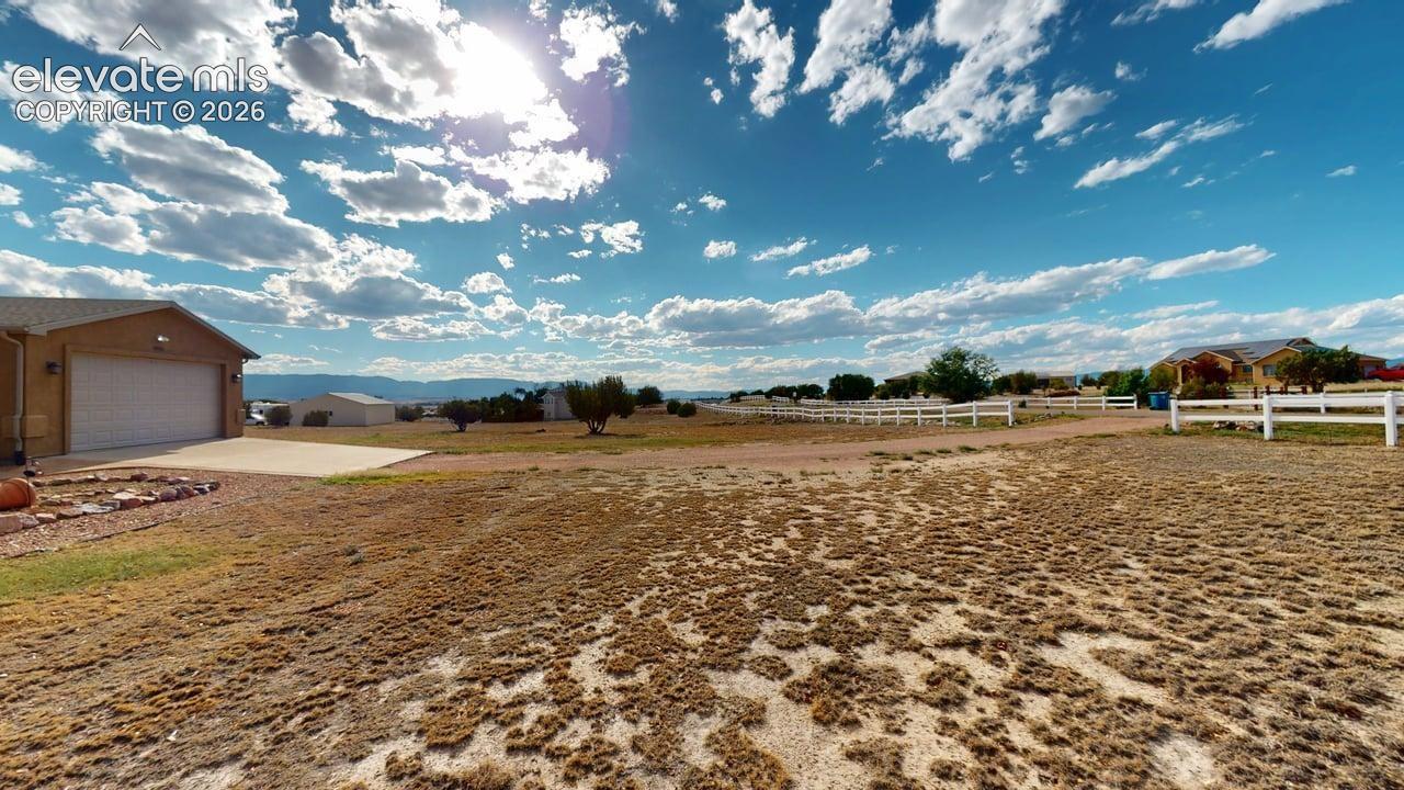 Expansive property with a detached garage, concrete driveway, and white perimeter fencing