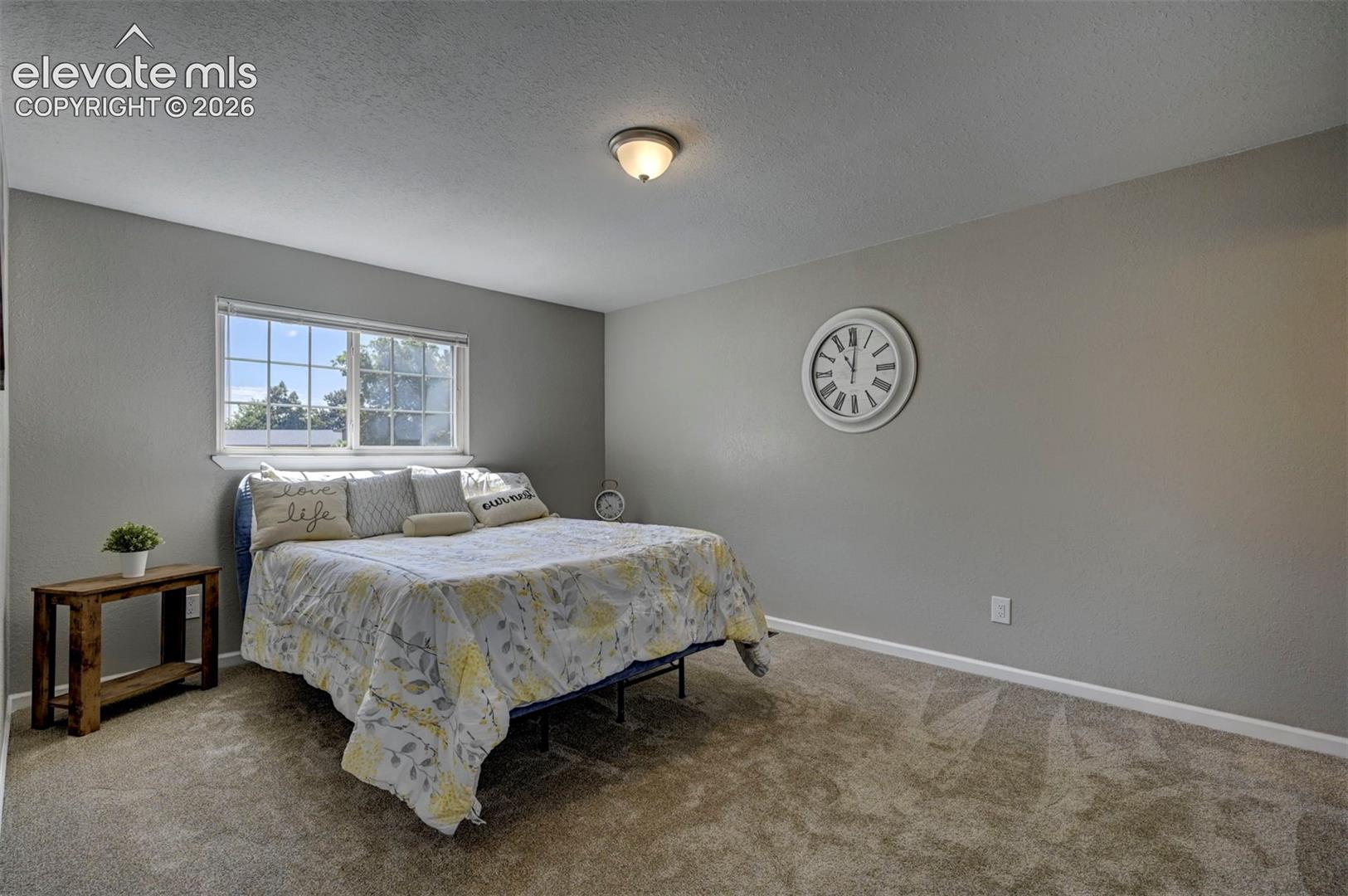 Neutral-toned interior space featuring wall-to-wall carpeting, a multi-pane window, and a semi-flush mount ceiling light fixture