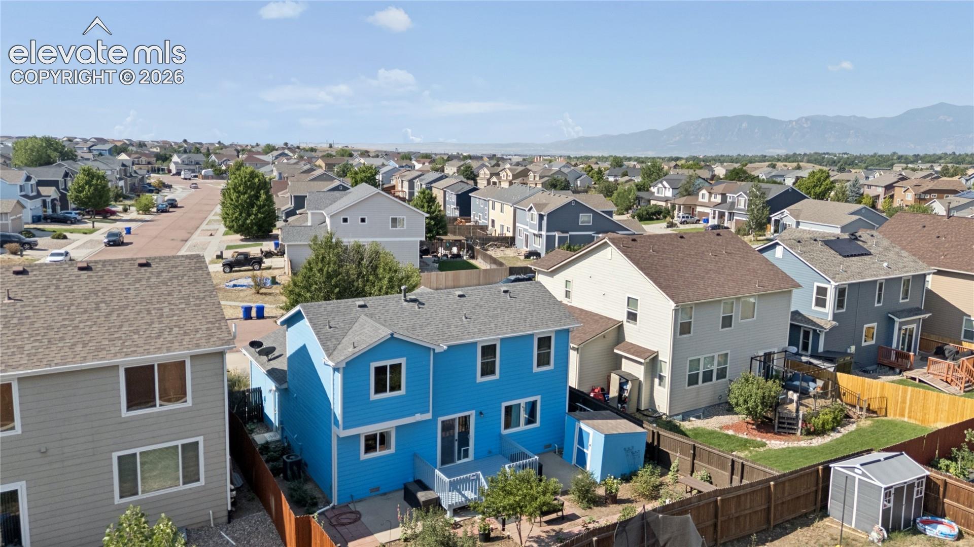 Residential structure with a blue siding exterior, a gray shingle roof, and a ground-level patio