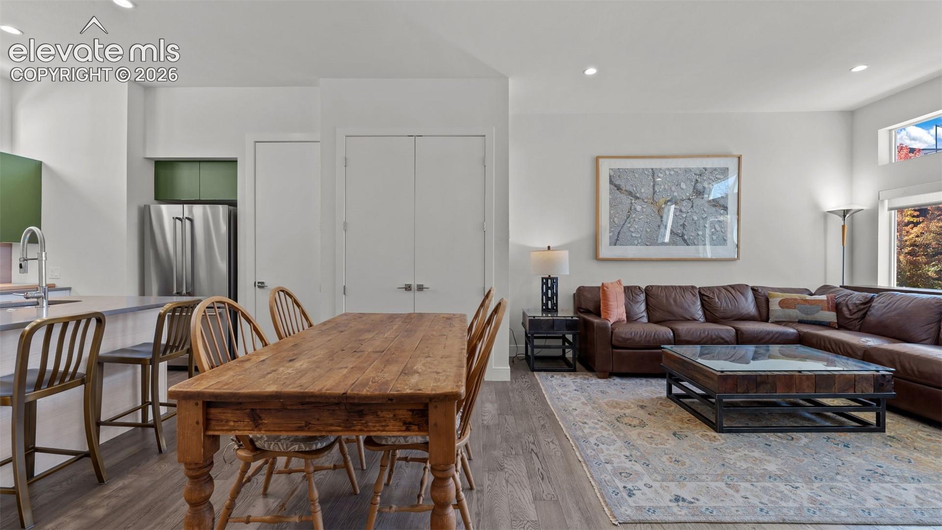 Open-concept space featuring wood-finish flooring, recessed lighting, and a breakfast bar with stone-surface countertops