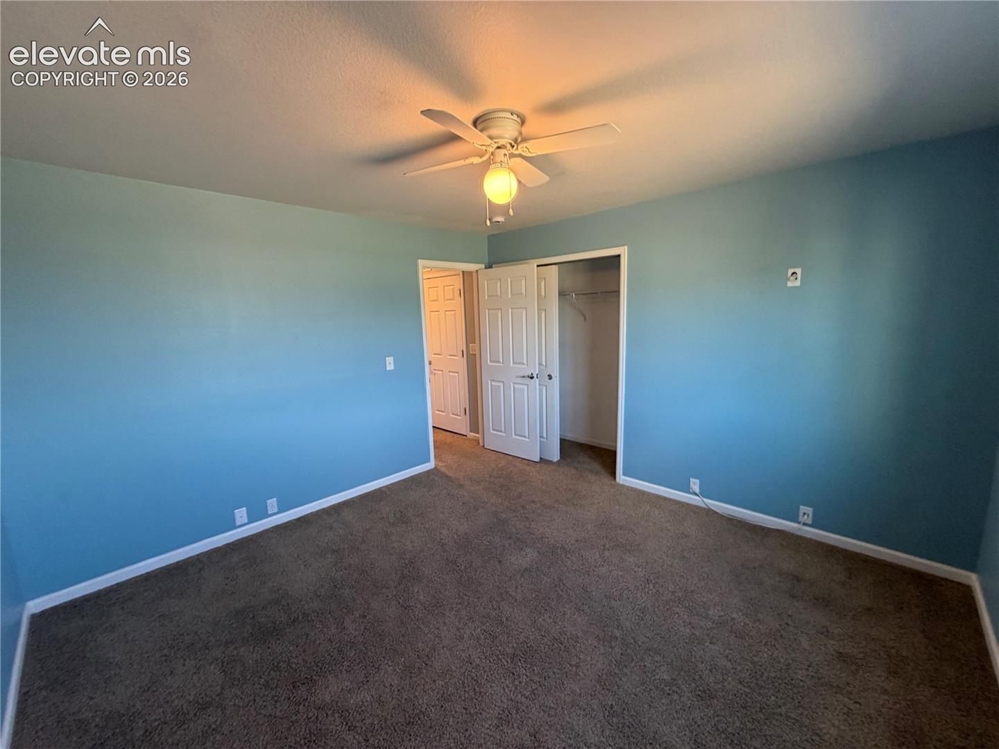 Ceiling fan, brown carpet, light blue walls, white trim, white paneled doors