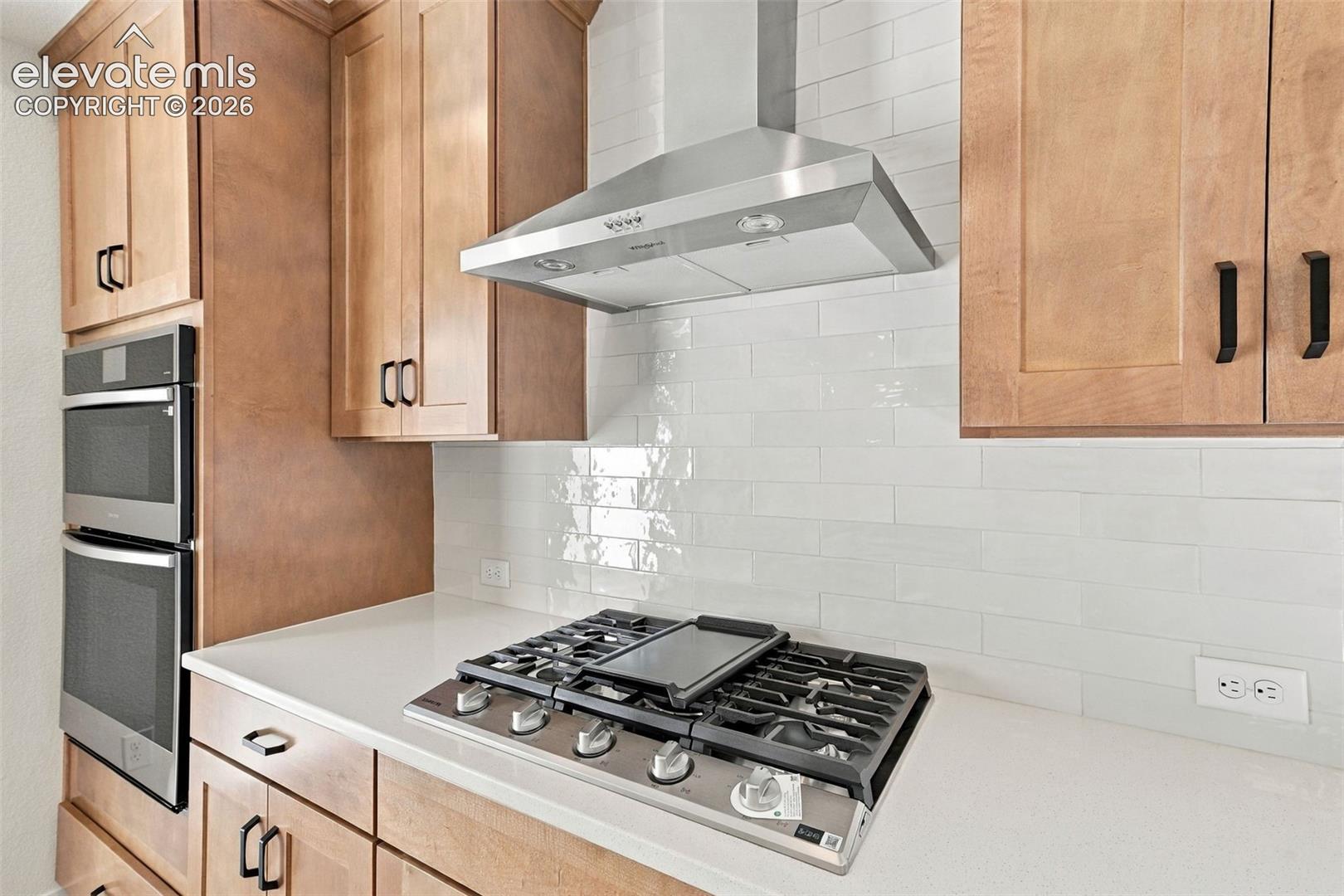 The Kitchen features stainless steel appliances, light maple cabinets with pecan stain, a large kitchen island with quartz countertop, and LVP flooring.