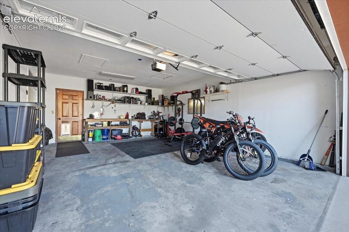 Attached garage featuring a light gray concrete floor, white walls, and a paneled garage door