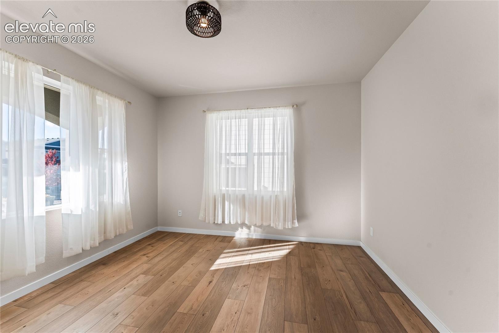 Wood-finish flooring, neutral wall tones, multi-pane windows, and a drum-style ceiling light fixture