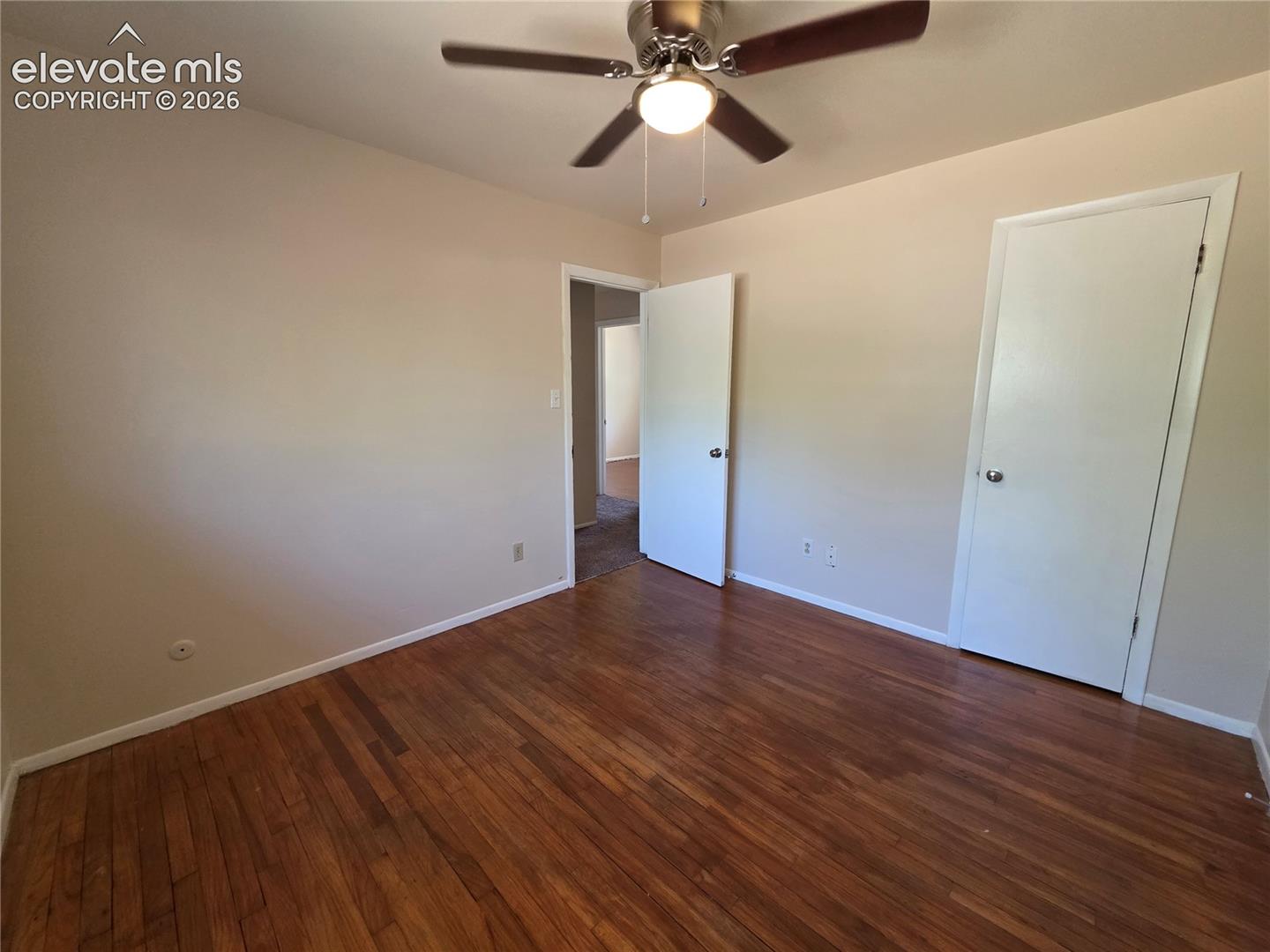 Bright interior room featuring wood-finish flooring and a ceiling fan with integrated lighting