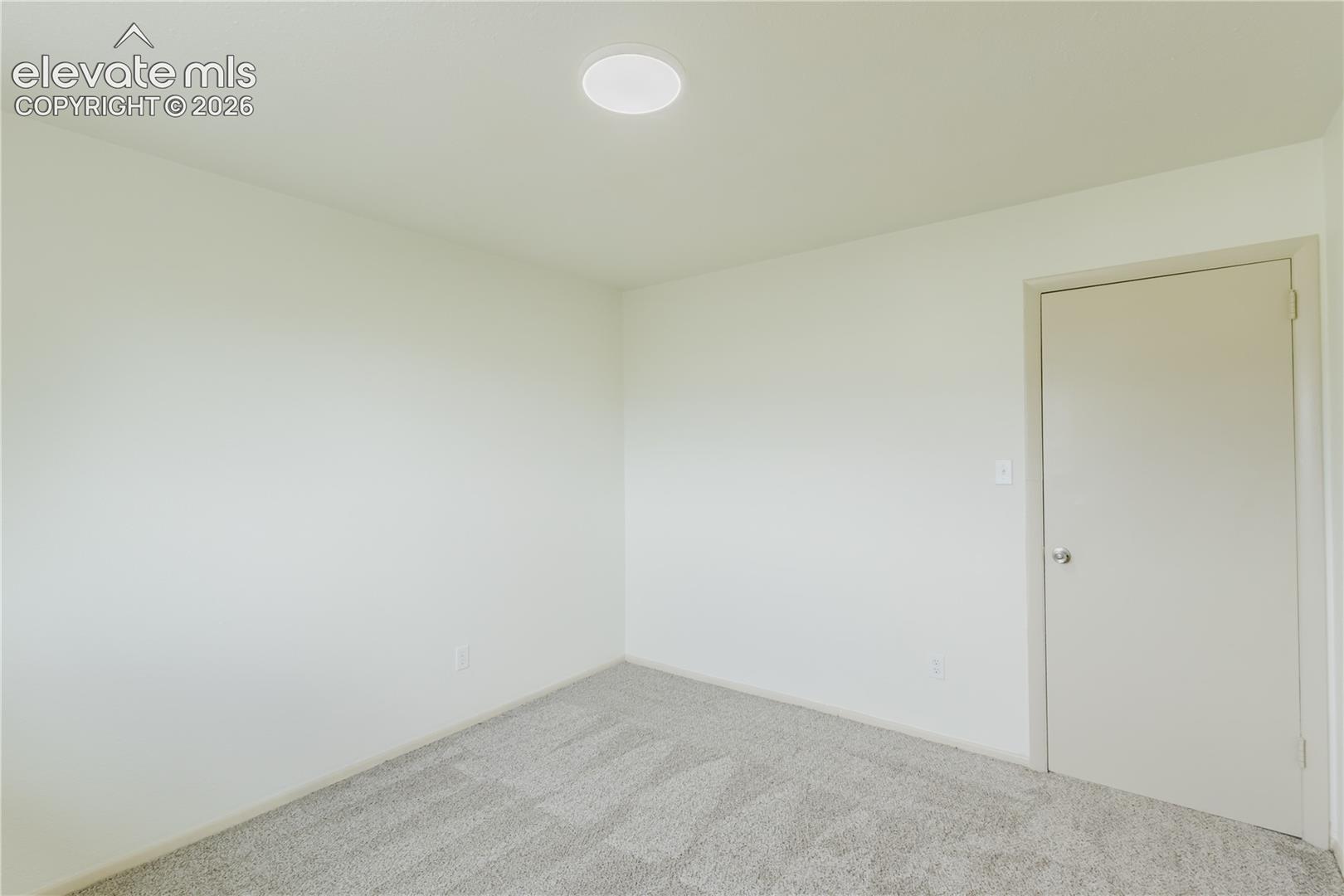 Interior room featuring neutral wall paint, light gray carpeting, a recessed ceiling light fixture, and a solid interior door