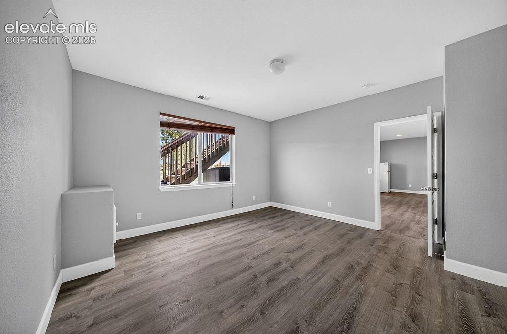 Wood-finish flooring, neutral gray wall tones, window with a wood-tone blind, and white trim throughout