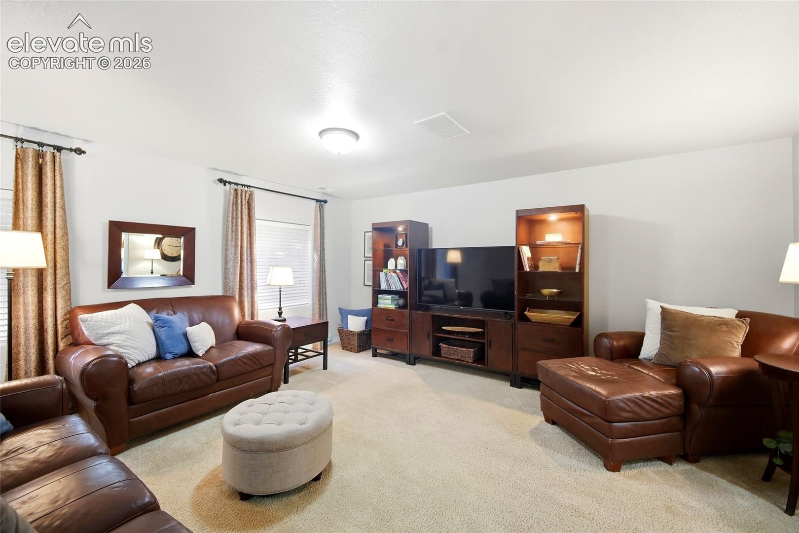 Recessed lighting, light beige carpeting, white walls, built-in media console, and window treatments
