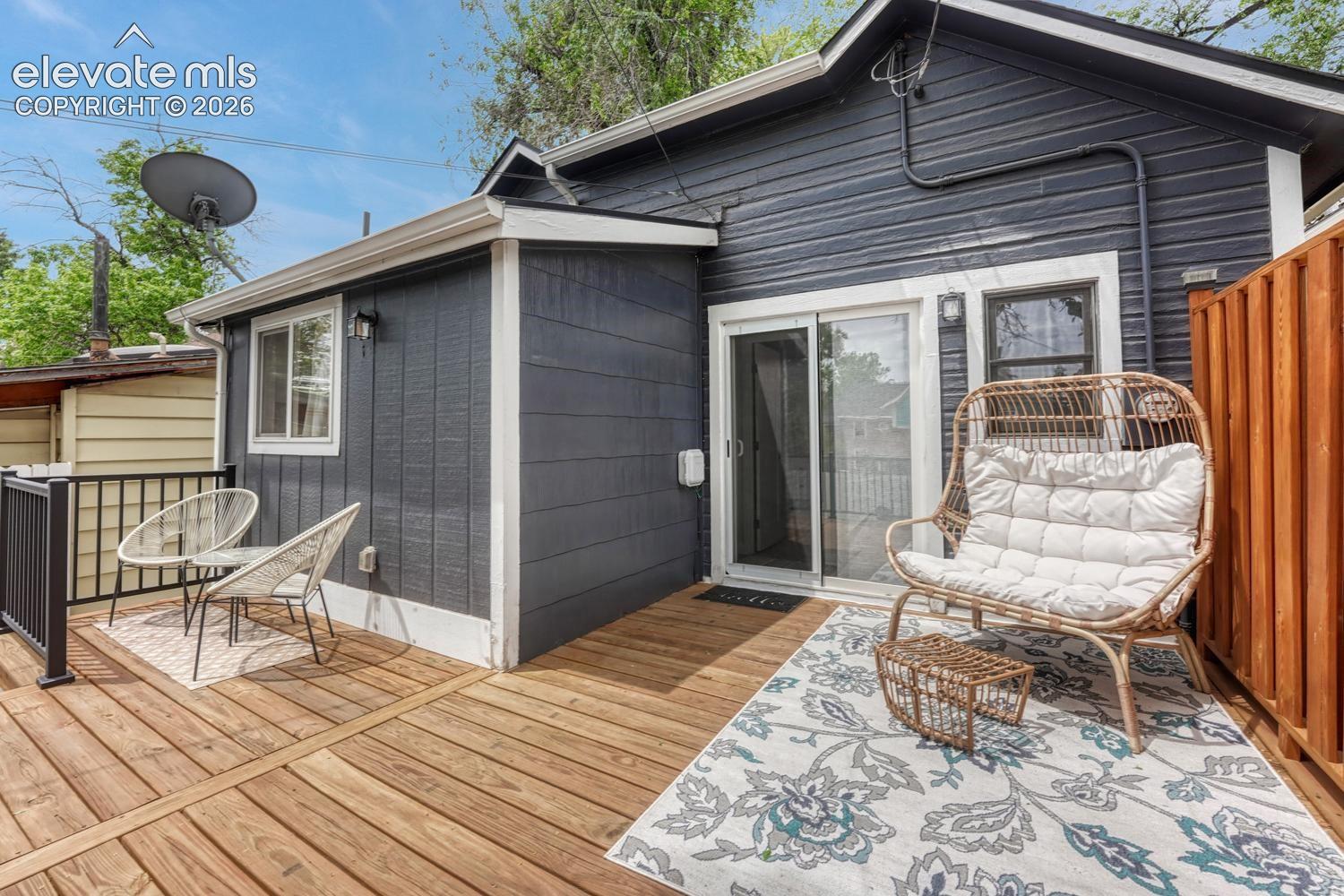 Expansive wood deck with a dark gray exterior, white trim, sliding glass door access, and privacy fencing