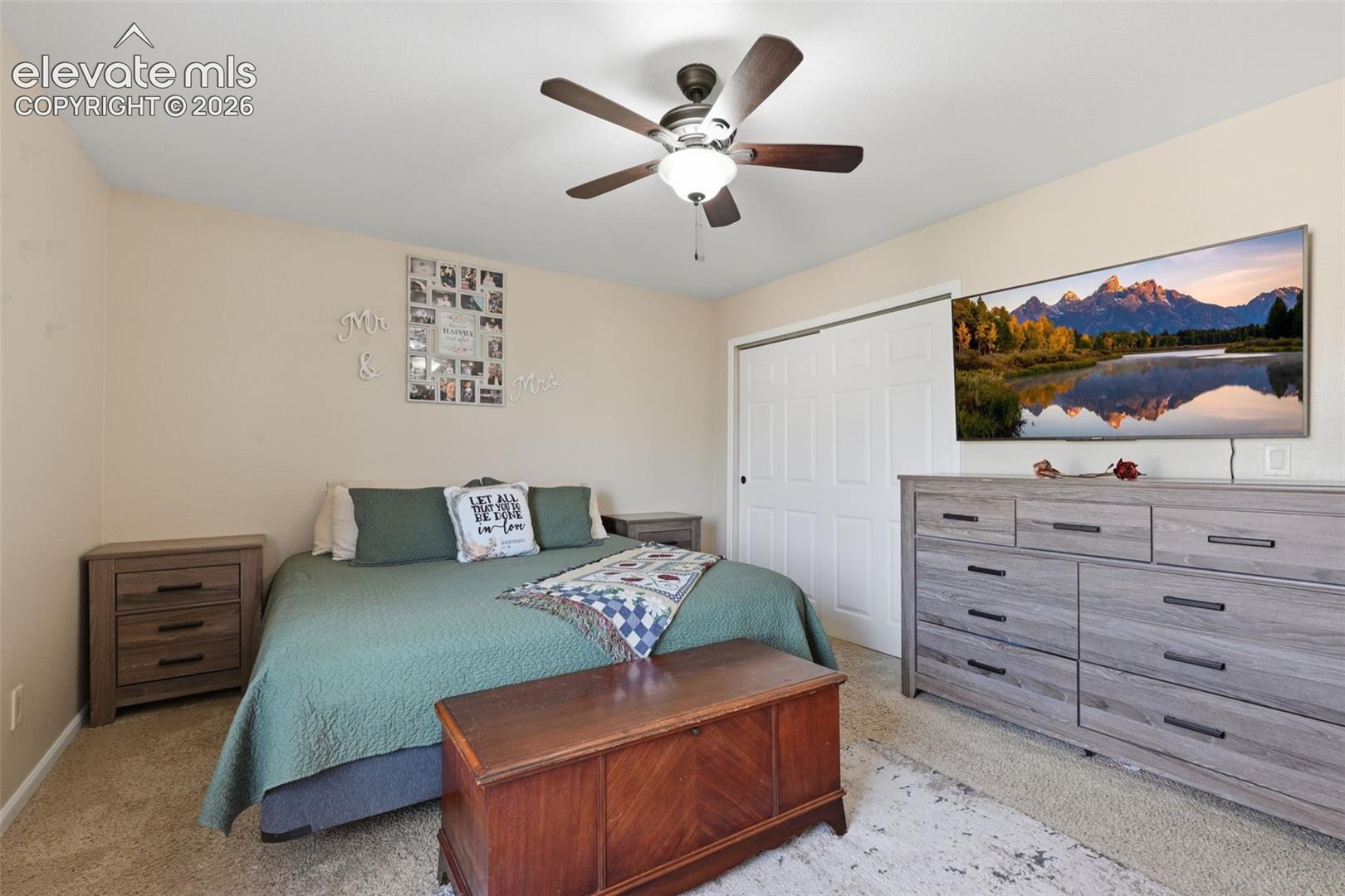 Bedroom featuring neutral wall paint, carpet flooring, a ceiling fan with integrated lighting, and a closet with bifold doors
