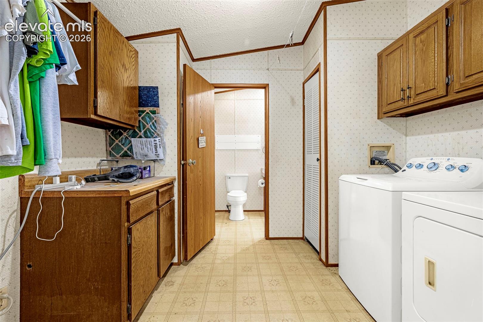 Laundry room featuring wood-finish cabinetry, countertop workspace, and linoleum flooring