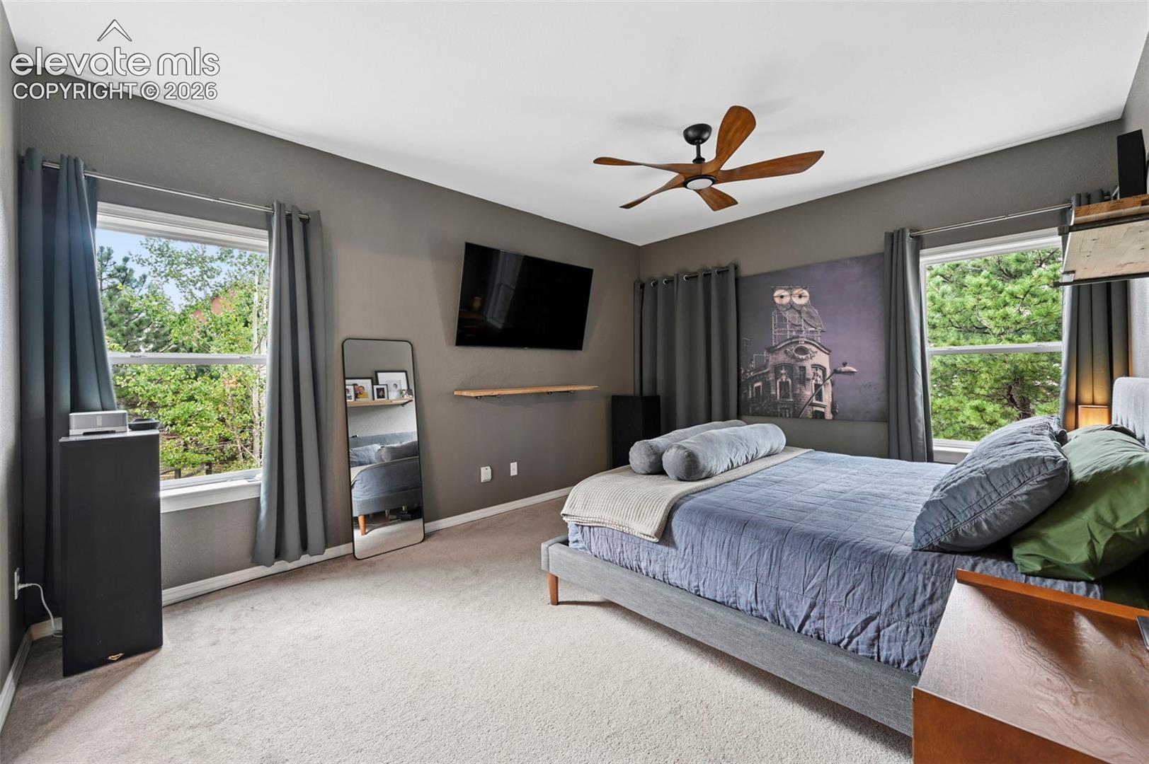 Recessed window frames, wood-finish ceiling fan, wall-mounted floating shelf, and carpeted flooring
