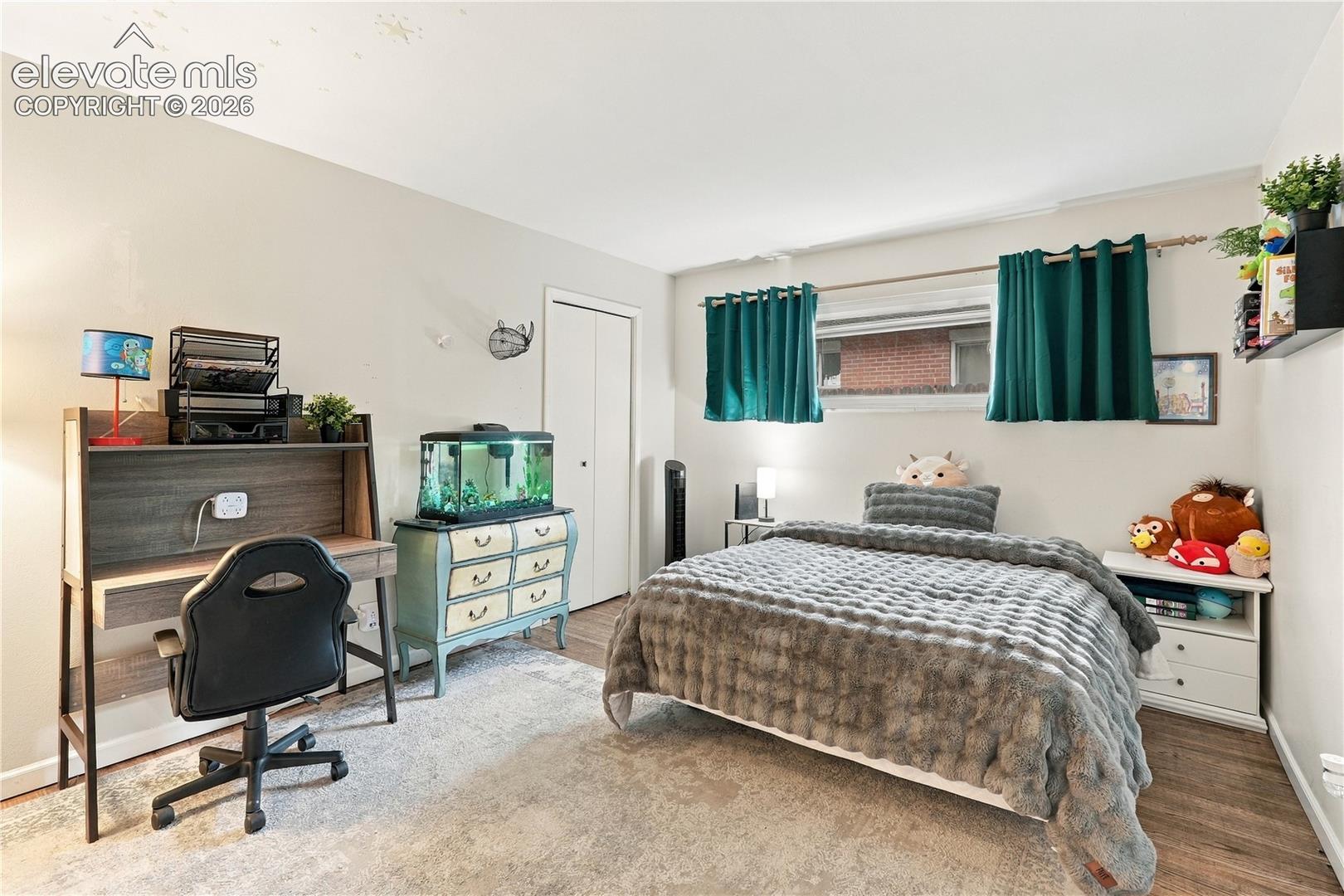 Room featuring wood-finish flooring, a horizontal rectangular window, and a built-in closet with double doors