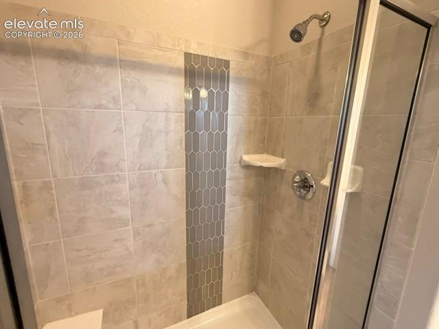 Tiled shower with a decorative vertical accent strip, chrome fixtures, and a glass enclosure