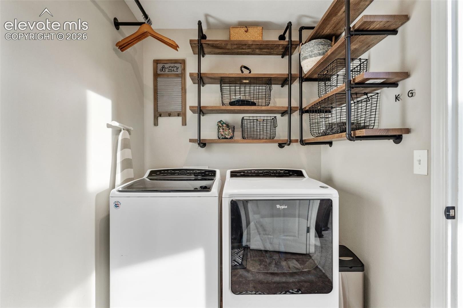 Industrial-style floating shelves featuring wood-finish planks and matte black pipe hardware, paired with integrated metal wall-mounted hanging rack