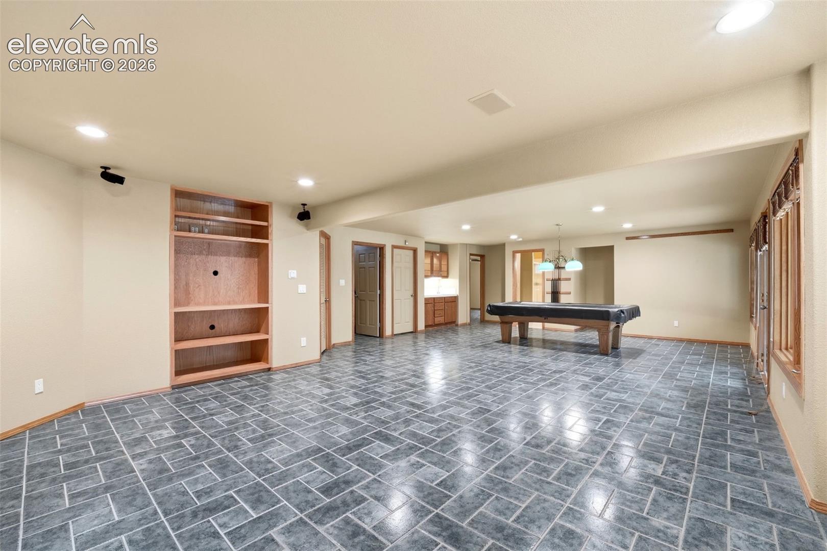 Spacious room featuring gray tile flooring, recessed lighting, and a built-in media center with integrated shelving
