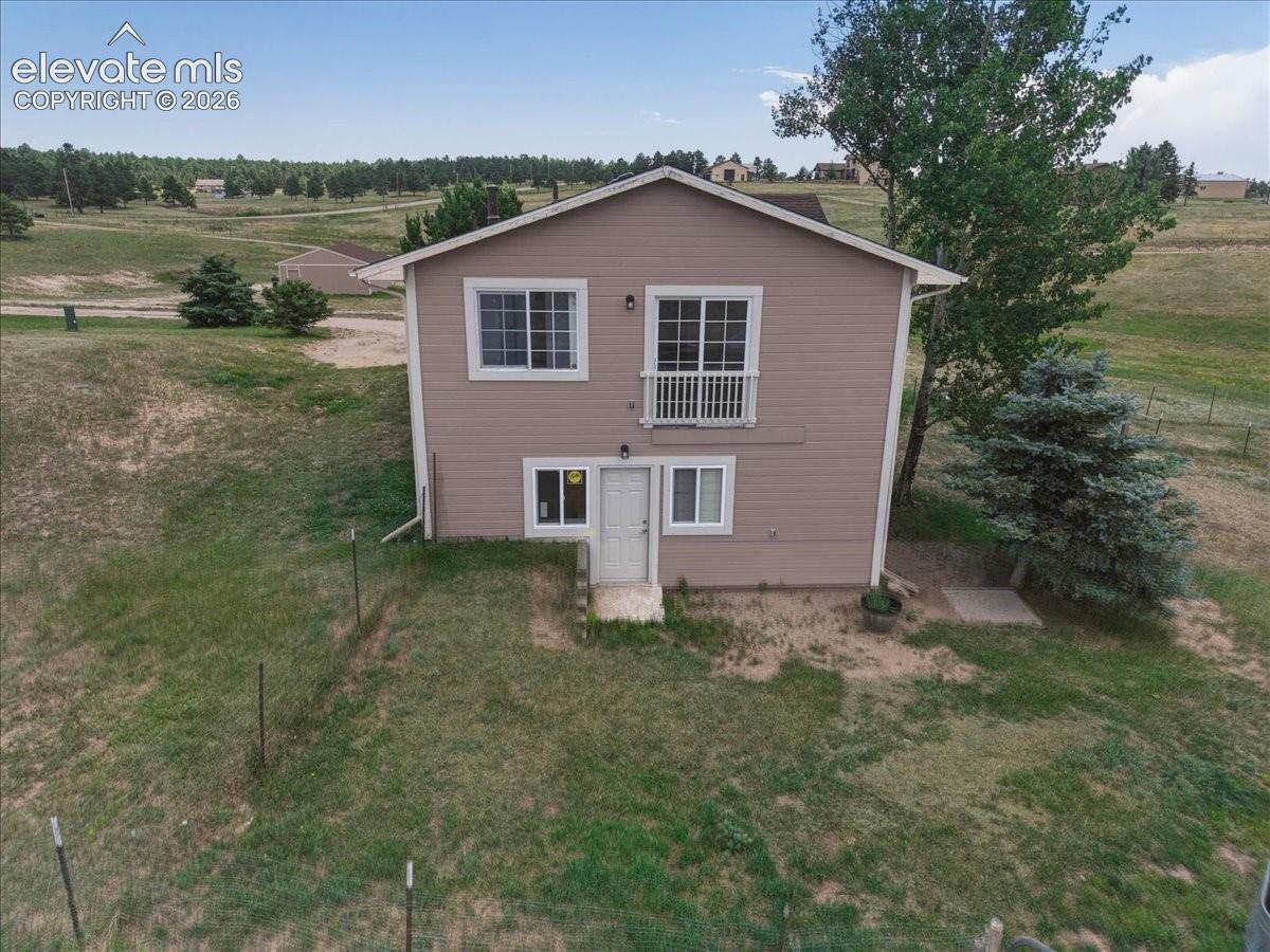 Two-story north side  exterior featuring lap siding, an upper-level balcony with railings, multiple sliding windows, and a concrete patio