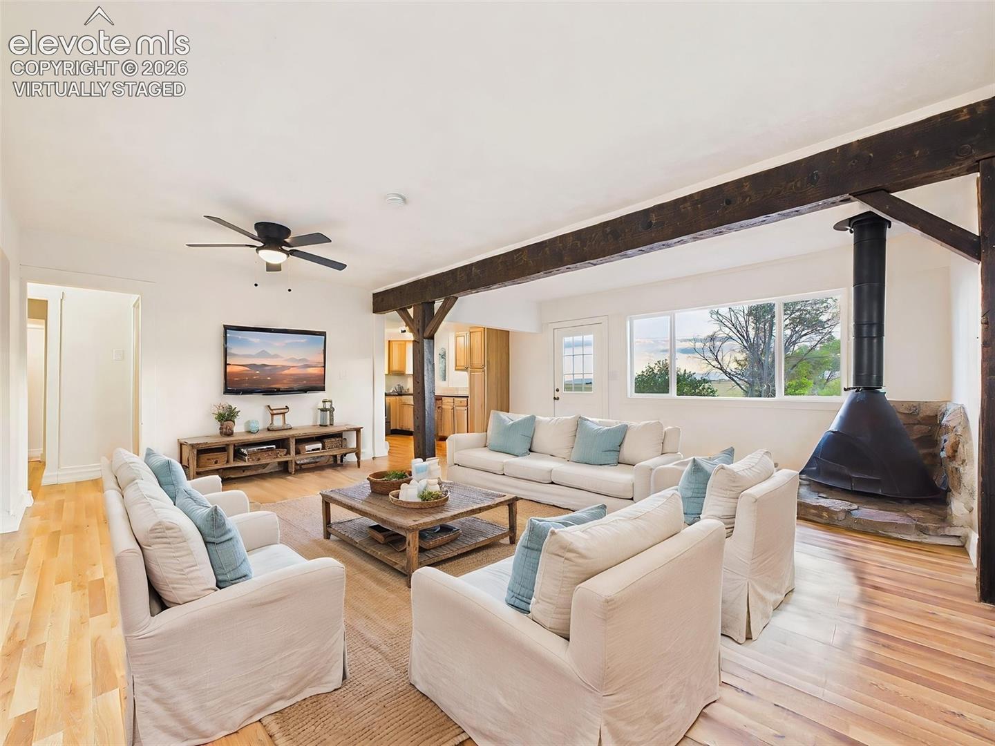 (Virtually Staged) Living Room – Another view of the inviting living space highlighting the dramatic beam accents, open layout, and cozy fireplace.