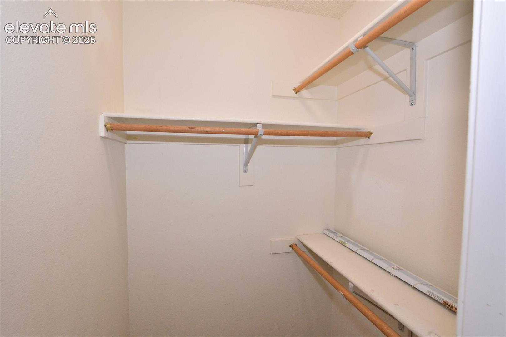 Built-in closet shelving with multiple hanging rods and an integrated ironing board