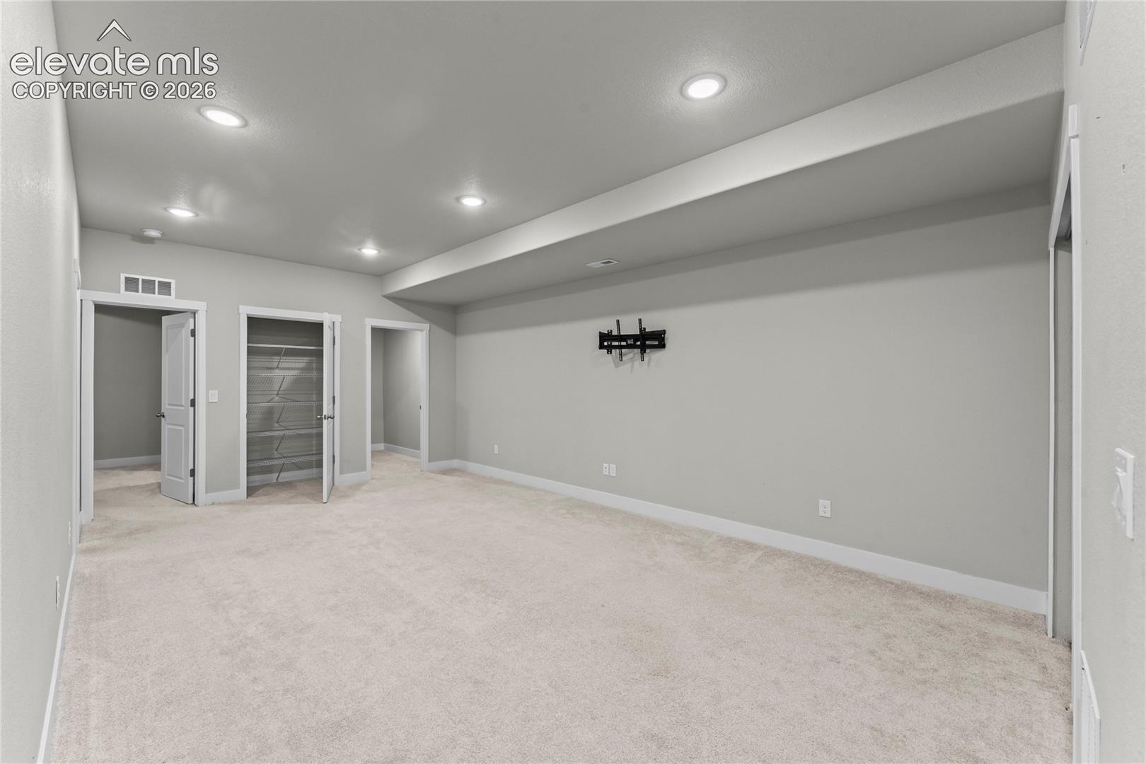 Spacious recreation room featuring recessed ceiling lighting, neutral carpet flooring, and multiple wall outlets