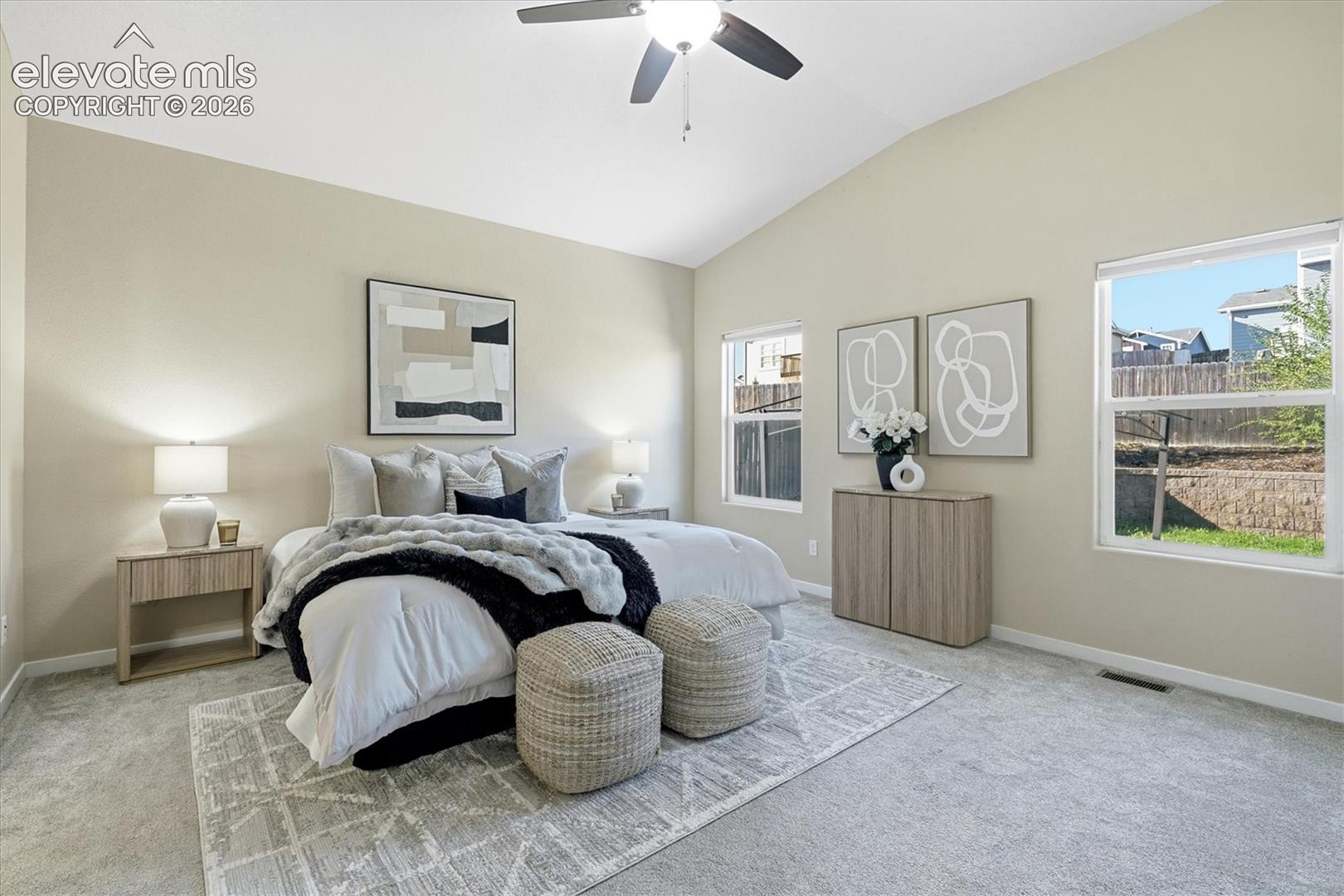 Vaulted ceiling with a ceiling fan, light gray wall paint, light gray carpeting, and multiple windows