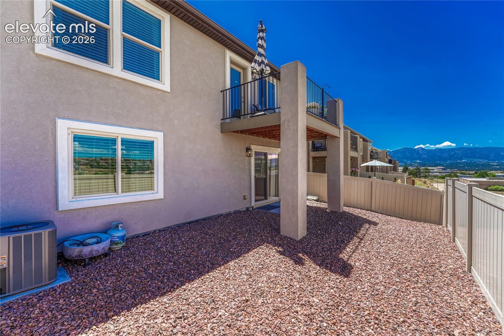 The rear exterior offers easy outdoor living with a low-maintenance yard, covered patio, and elevated balcony overlooking the surrounding landscape.