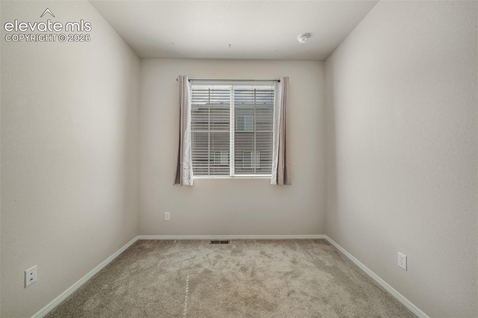 Neutral tone wall paint, window with blinds, and carpeted flooring