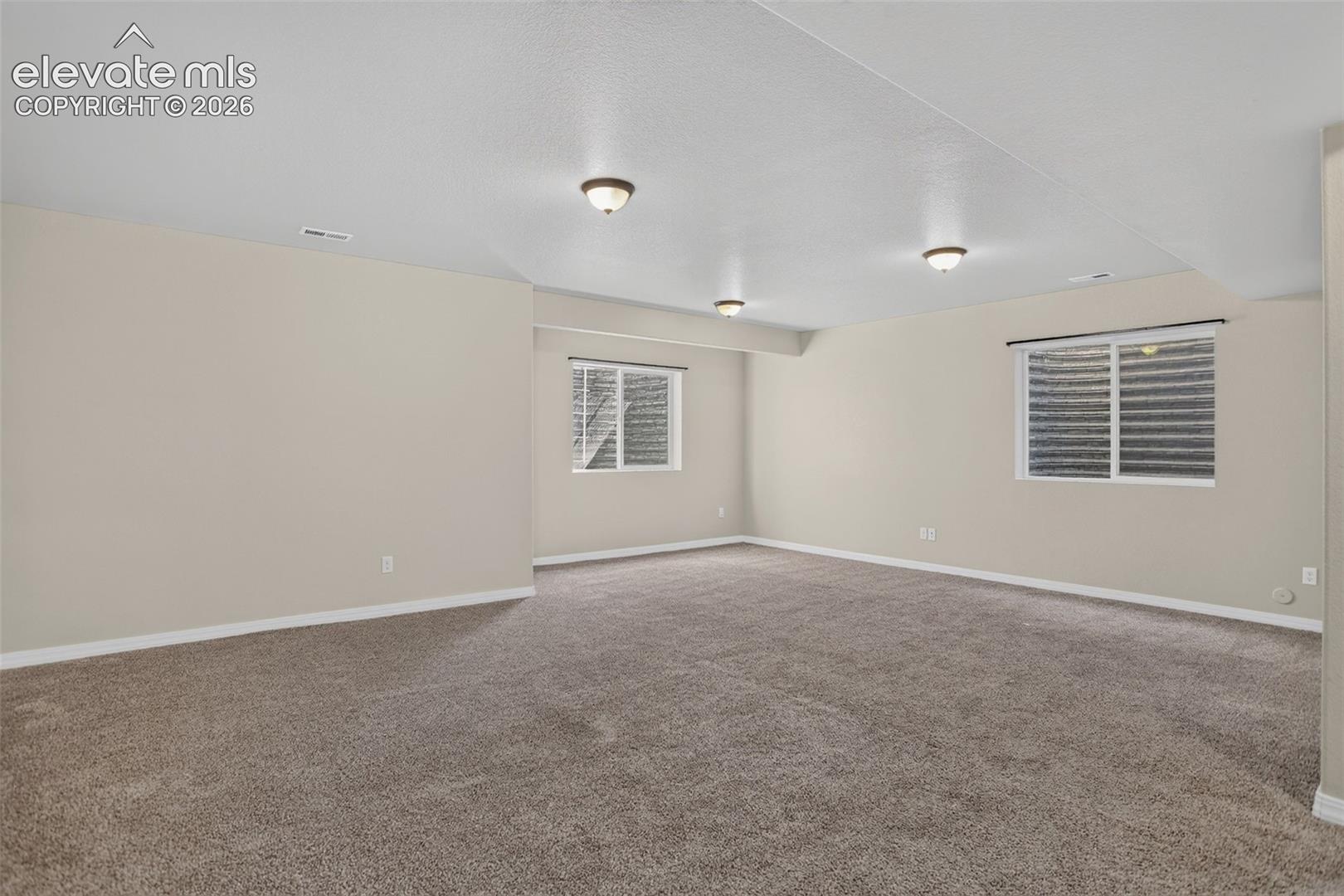 Carpeted living space featuring recessed lighting and multiple windows with blinds