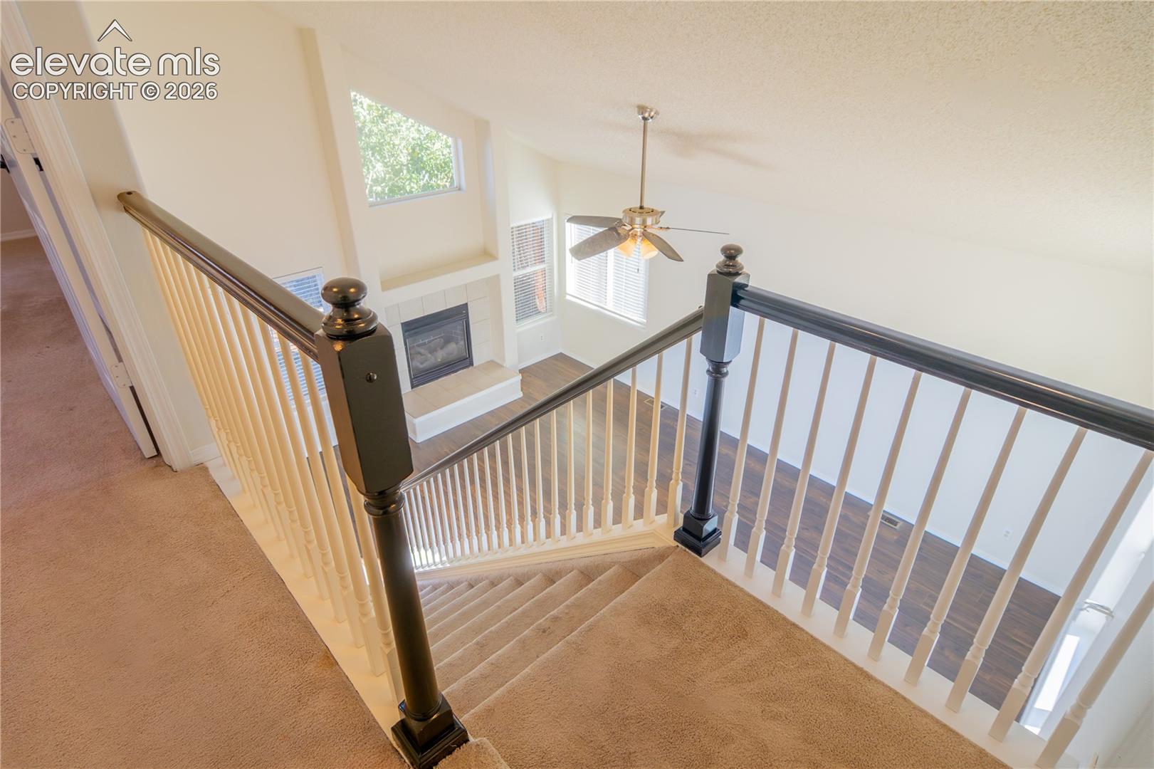 A beautiful view of the vaulted living room, fireplace, and expansive windows from above.